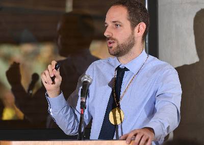 François Greer, assistant professor of mathematics and the inaugural Van Haften Endowed Professor of Deductive Literacy giving his research presentation at a podium in the front of the room during his investiture. 