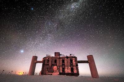 IceCube at twilight, with a starry sky showing a glimpse of the Milky Way overhead and sunlight lingering on the horizon. 