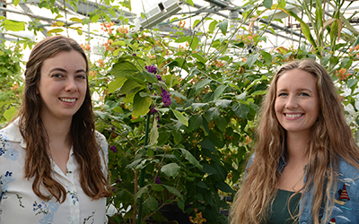 Emily Lanier and Abigail Bryson standing in a greenhouse with beatyberries in the background.