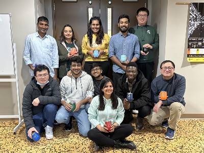 Photo of the Tuo Wang research group posing outside of thier lab in the MSU Chemistry Building.