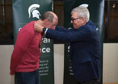 Doug Gage, vice president of the Office of Research and Innovation at MSU, places an endowed faculty medallion around Dr. Sean Crosson's neck to symbolize his installment as a Rudolph Hugh Endowed Chair.