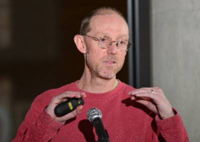 Sean Crosson geturing as he makes a point at the podium during his investiture research presentation