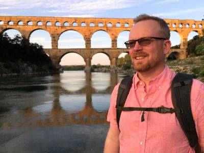 Jay Zarnetske stanidn in front of an ancient Roman aqueduct bridge in France.