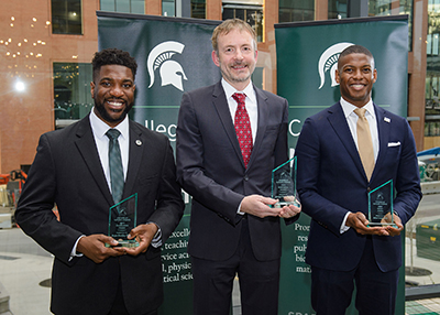 2023 NatSci award recipients posing between green and white College of Natural Science banners (left to right): Bryan O. Buckley, Outstanding Alumni Award; Michael Feig, Meritorious Faculty Award; and Jelani Zarif, Recent Alumni Award.