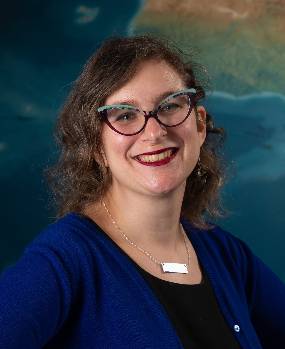 Headshot of Shannon Schmoll standing in front of a mural in MSU's Abrams Planetarium.