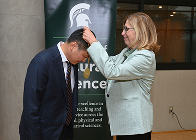Tuo Wang receives his endowed faculty medallion from MSU Interim President Teresa K. Woodruff, Ph.D.