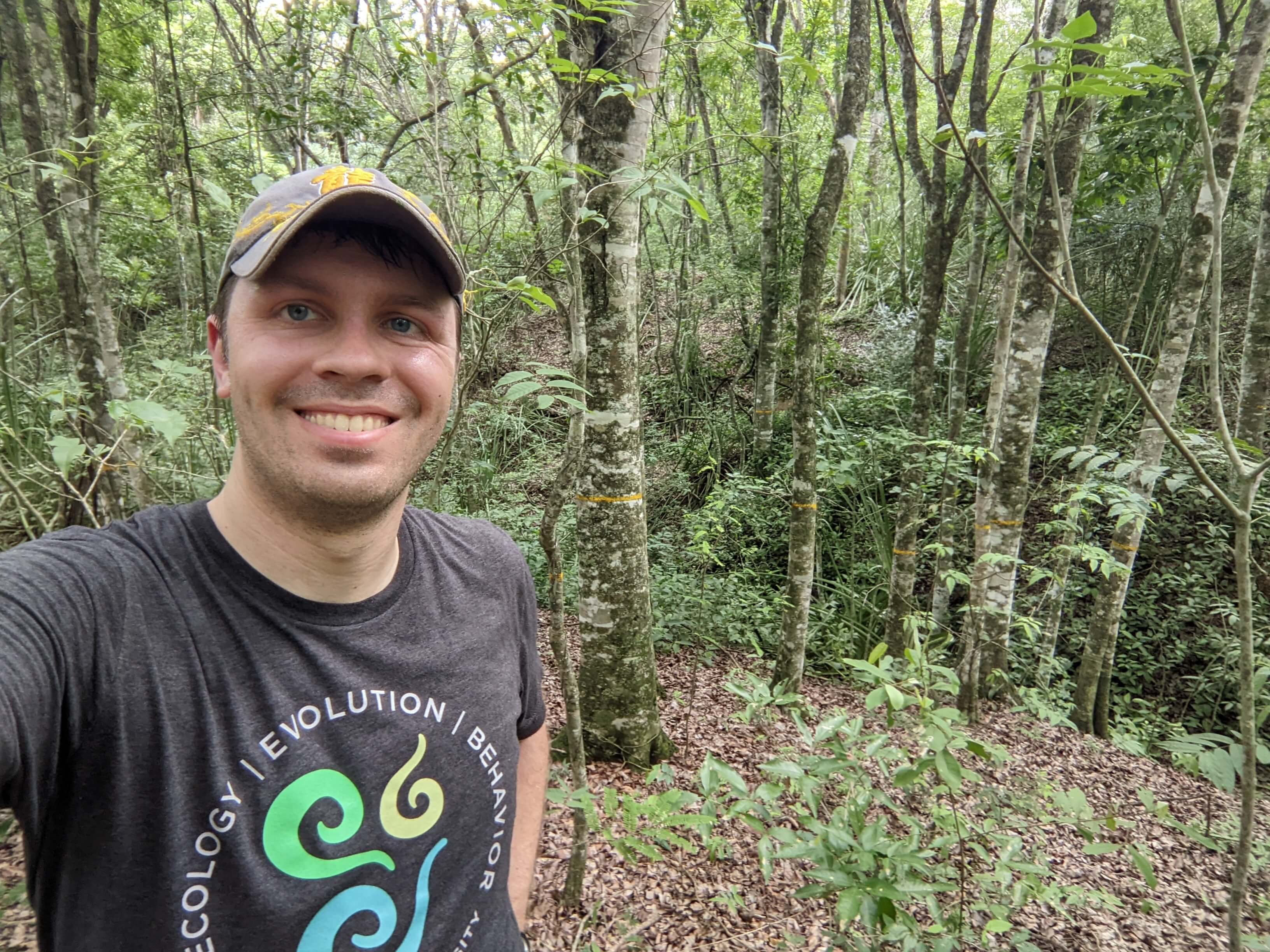 Peter Williams takes a selfie in Colombia, surrounded by trees with lush green leaves.