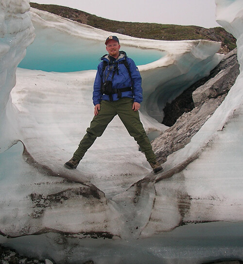 Jay Zarnetske stands on an aufeis — a seasonal mass of layered ice that forms when ground or stream water is exposed to freezing temperatures during the long, cold Arctic winter months.
