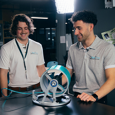 Austin Pollock and Alex Pollock stand next to their invention, the Reel Free, a spool-like device that helps manage oxygen tubing to reduce tripping risks