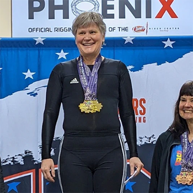 Marianne Huebner stands on a podium wearing a medal