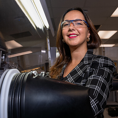 Selvan Demir poses for a photo while working with her arms inside a glovebox.