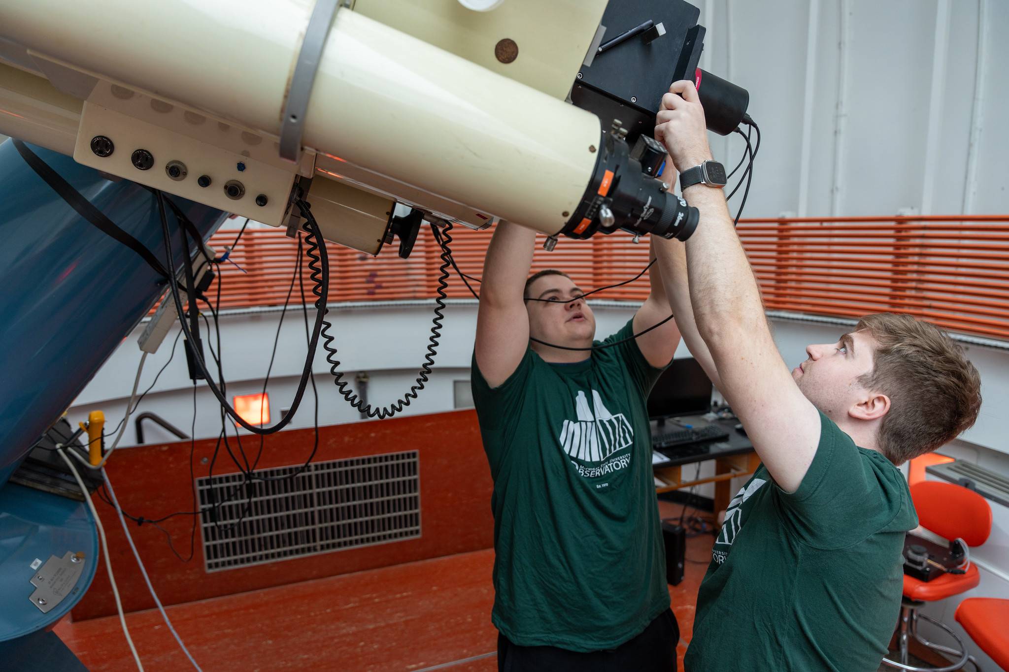 Two MSU students adjust the camera on a research telescope