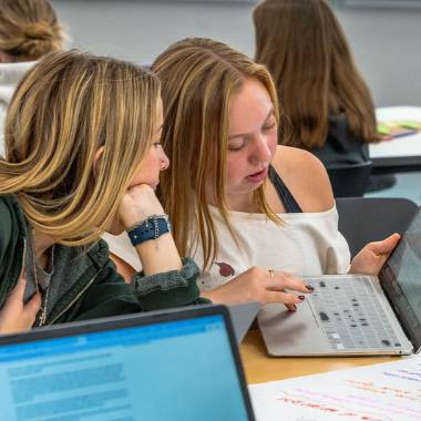 Two students look at an article on a computer