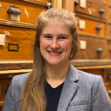 A woman in a suit standing in front of drawers