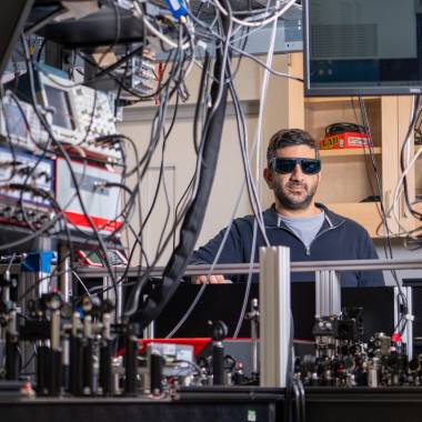 Elad Harel standing next to his lab equipment.