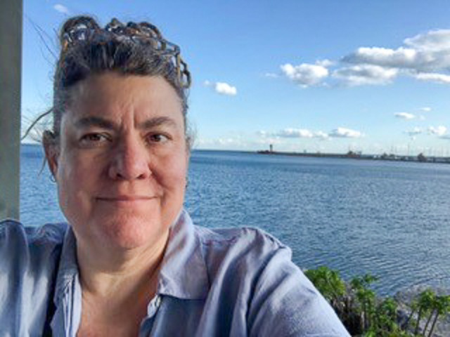 IBIO professor Heather Eisthen smiles at the camera. Behind her, a large body of water is visible.