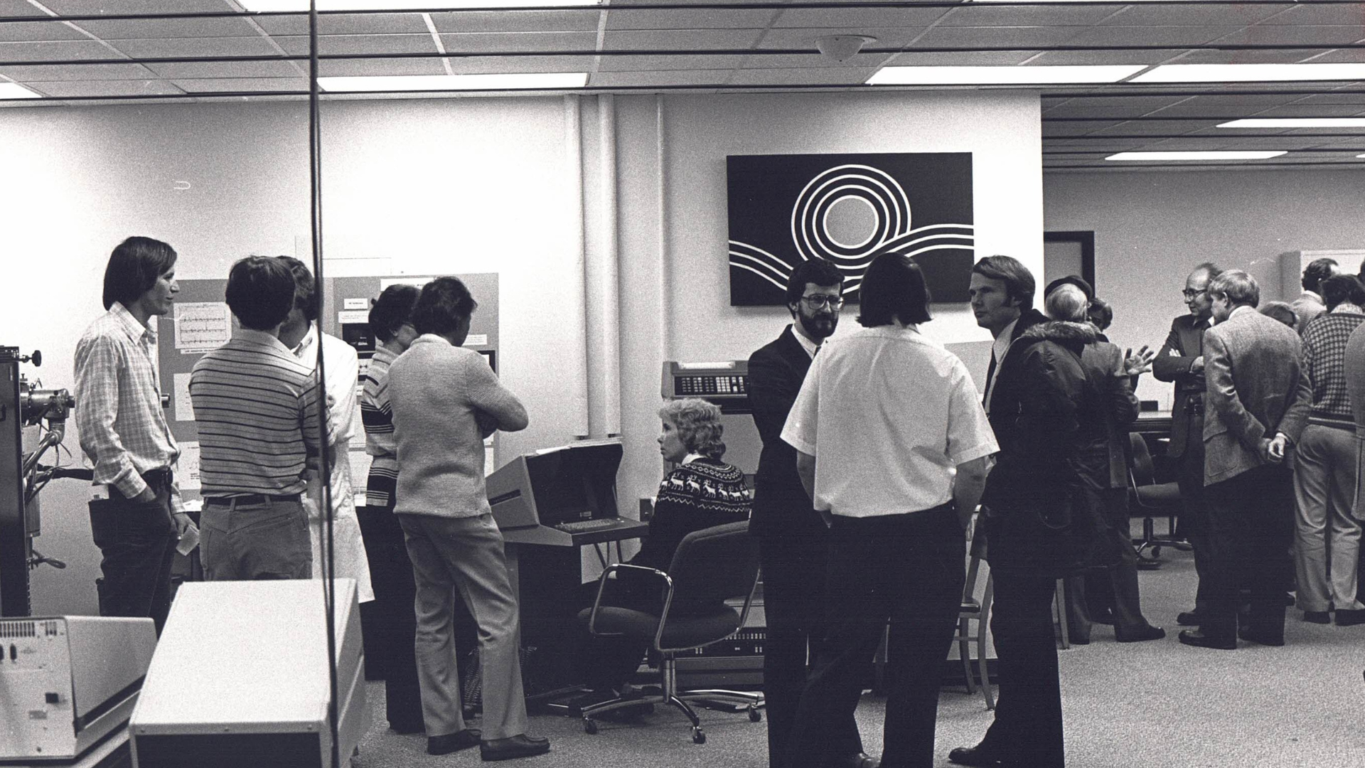 Black and white photo of MSU's Mass Spec core from the 60s-70s. Groups of scientists converse in groups.