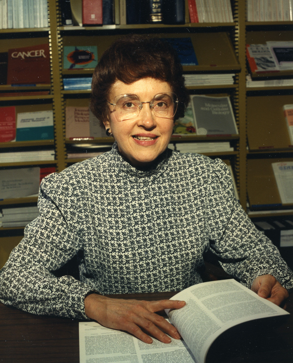 A portrait of Veronica Maher. She is sitting with an open book in front of her.