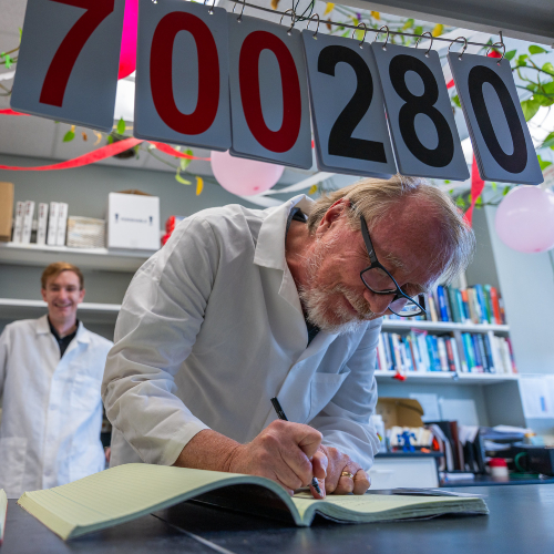 Richard Lenski updates the lab book under sign of numbers to count e.coli colony generations