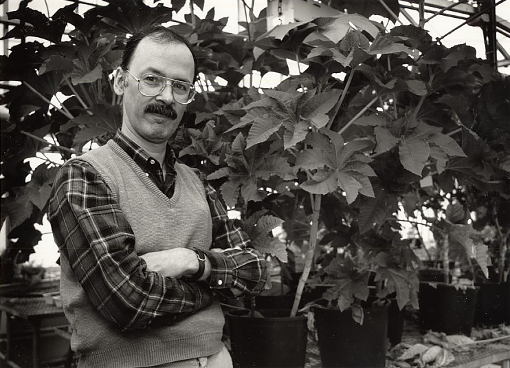 A balck and white image of a man in a greenhouse