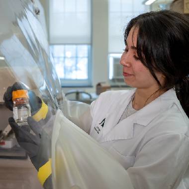 Woman in white coat working under hood