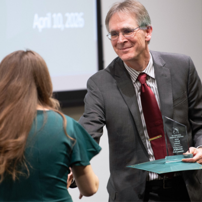 Dean Eric Hegg shakes hands with an Alumni Award winner