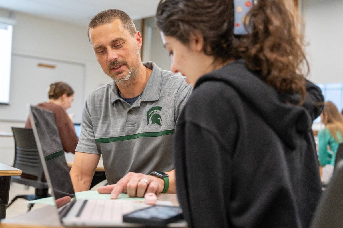 faculty and student review tasks at a laptop computer