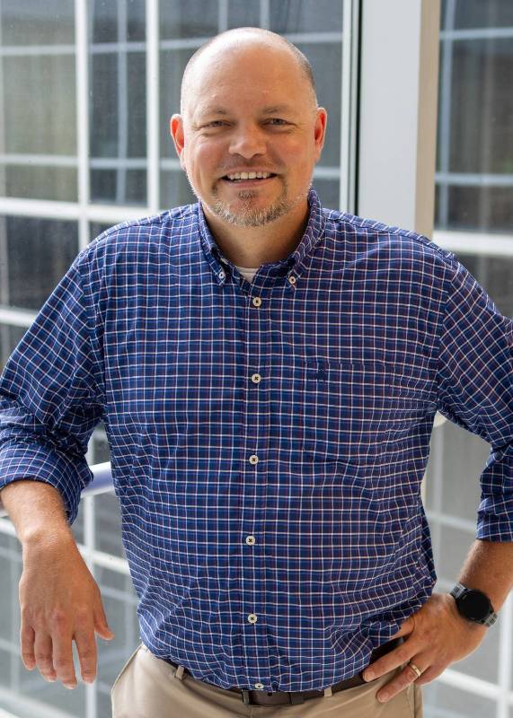 Man in a blue button down shirt poses for the camera
