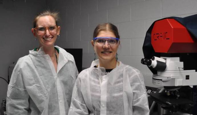 Researchers pose in a lab wearing protective coats.