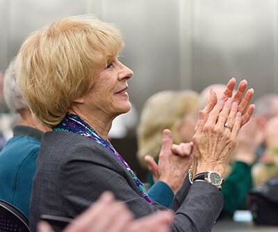 A female alumnus at an event standing and clapping