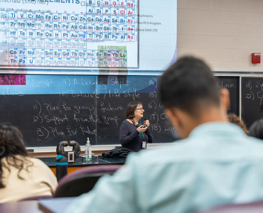 teacher in front of a blackboard teaching a lesson