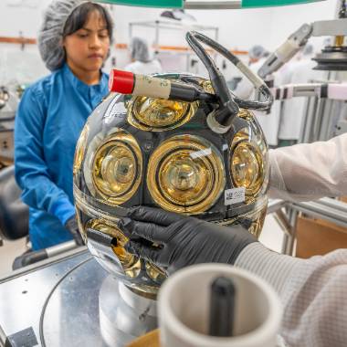 Alejandra Granados, a graduate student specializing in particle astrophysics, inspects a nearly completed digital optical module. Photo by Derrick L. Turner