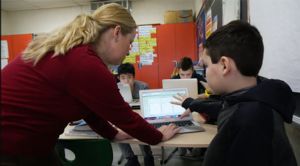 Image of a teacher working with a student on the computer.