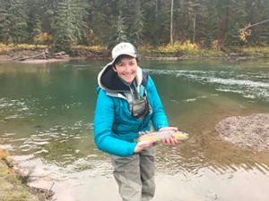 Image of Sarah Fitzpatrick standing in a stream holding a fish