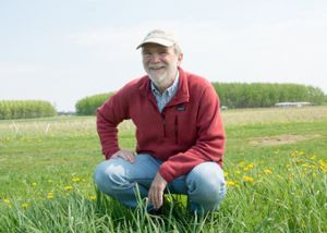 Phil Robertson, an internationally recognized crop and soil scientist and ecosystem ecologist kneels in a field at the Kellogg Biological Station.
