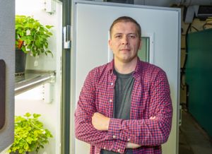 Image of Patrick Edger standing by a plant growing chamber in his lab. 